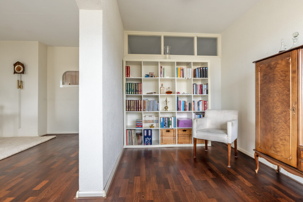 Cozy living room with bookshelf and chair.