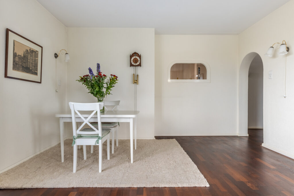 Minimalist dining room with white table and flowers.