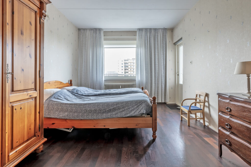Cozy bedroom with wooden furniture and large window.