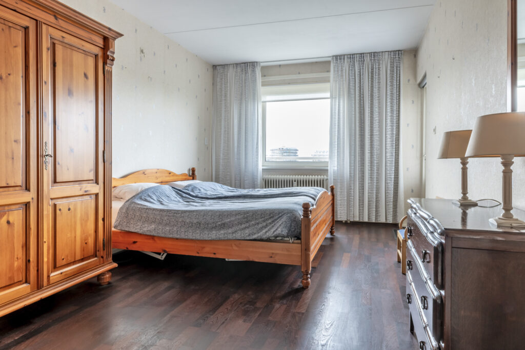 Cozy bedroom with wooden furniture and large window.