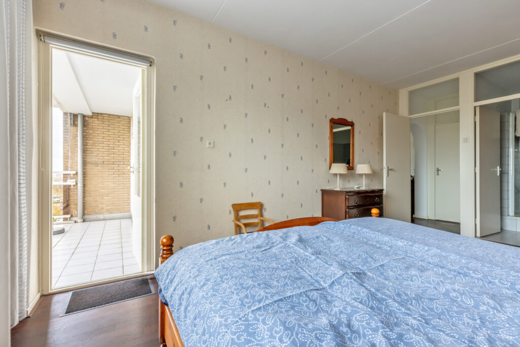 Bedroom with balcony access and classic furniture.