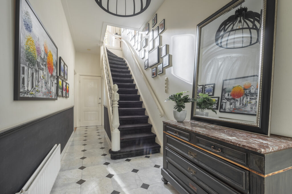 Elegant hallway with staircase and wall art displays.
