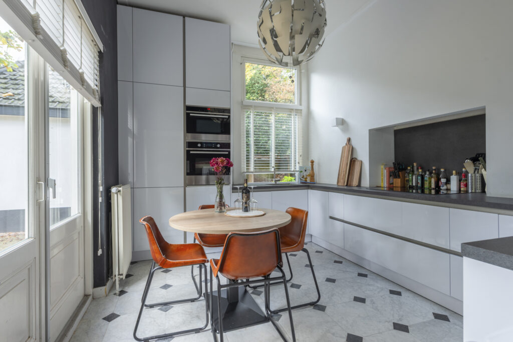 Modern kitchen with round table and orange chairs.