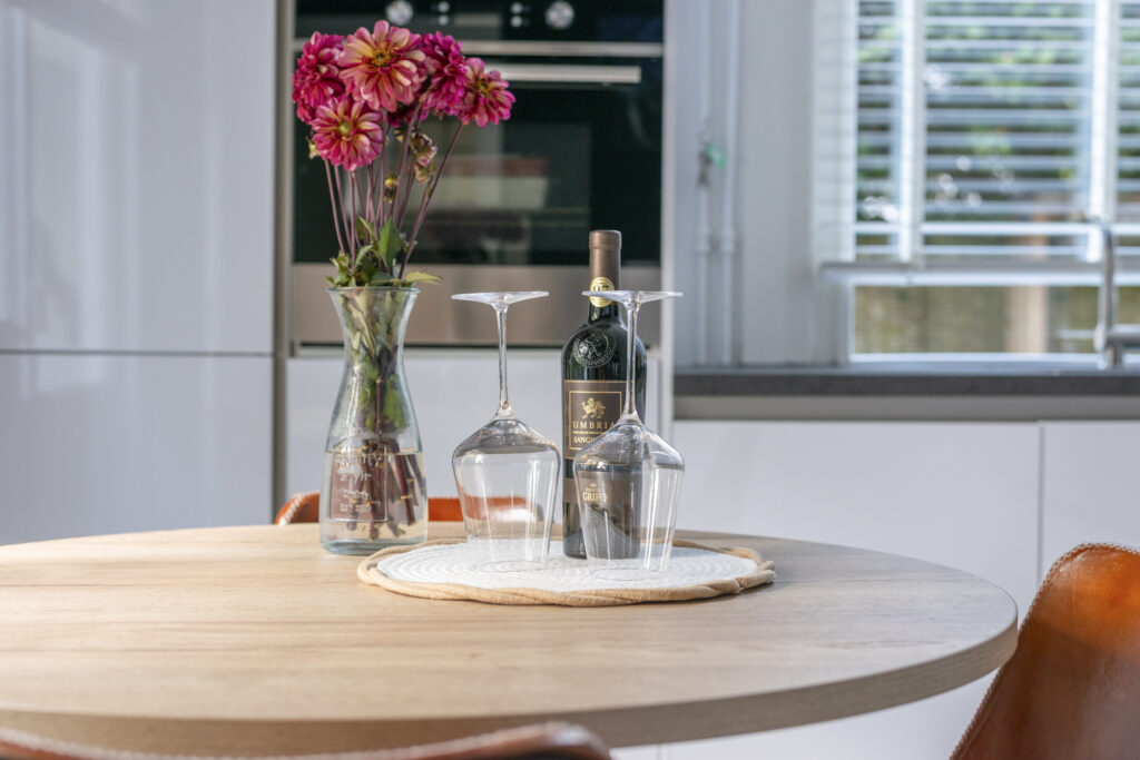 Table with flowers, wine bottle, and glasses.