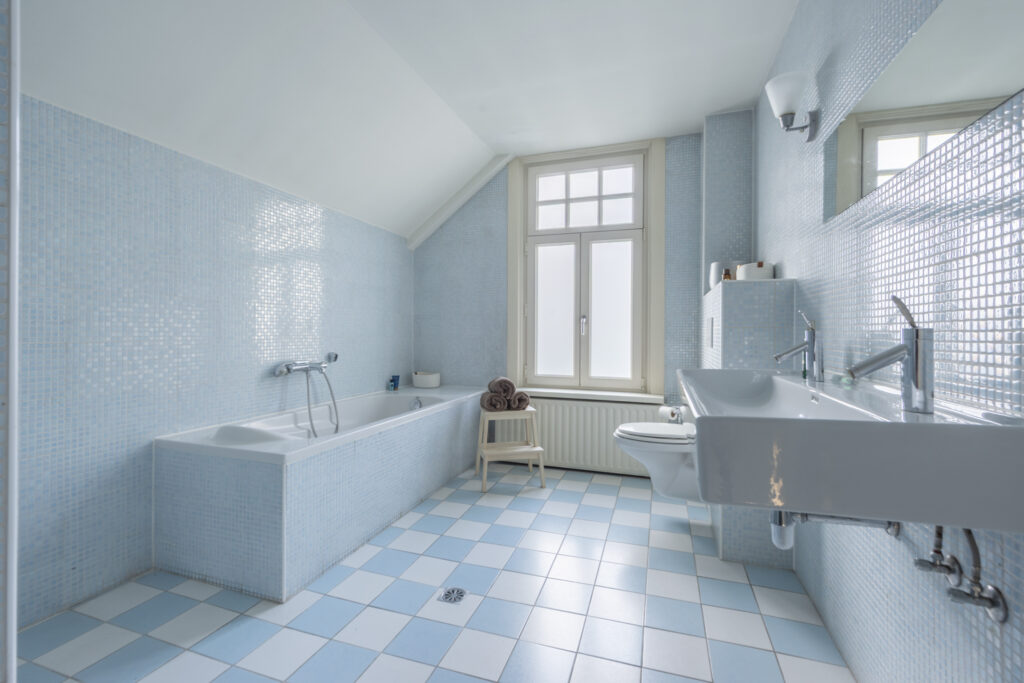Modern bathroom with blue tiles and bathtub.
