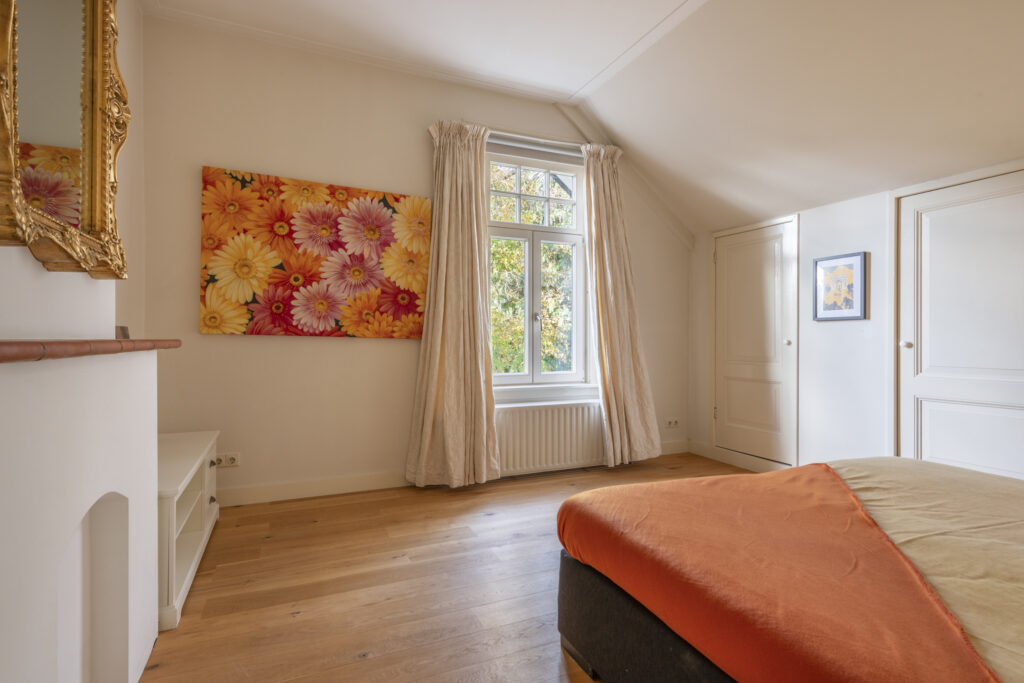 Bedroom with floral artwork and sunny window view.