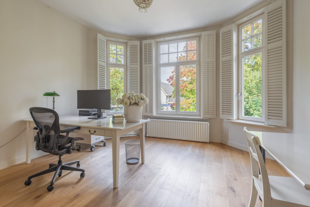 Bright home office with desk and large windows.