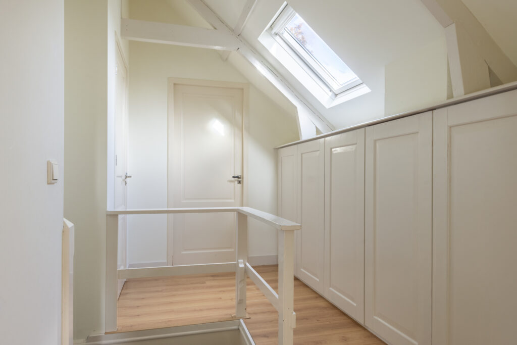 White attic hallway with skylight and wooden floor.