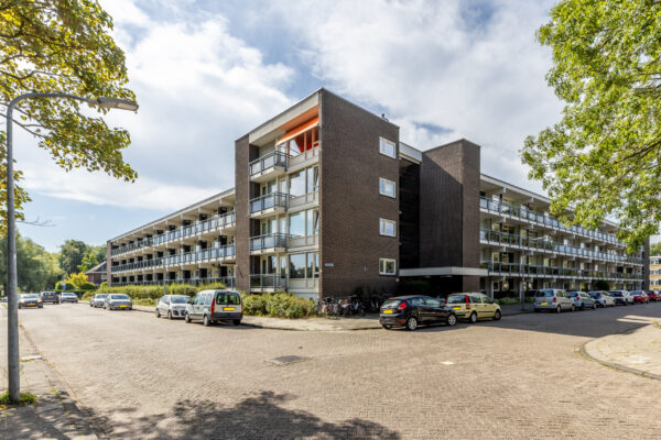 Apartment building with parked cars on street.