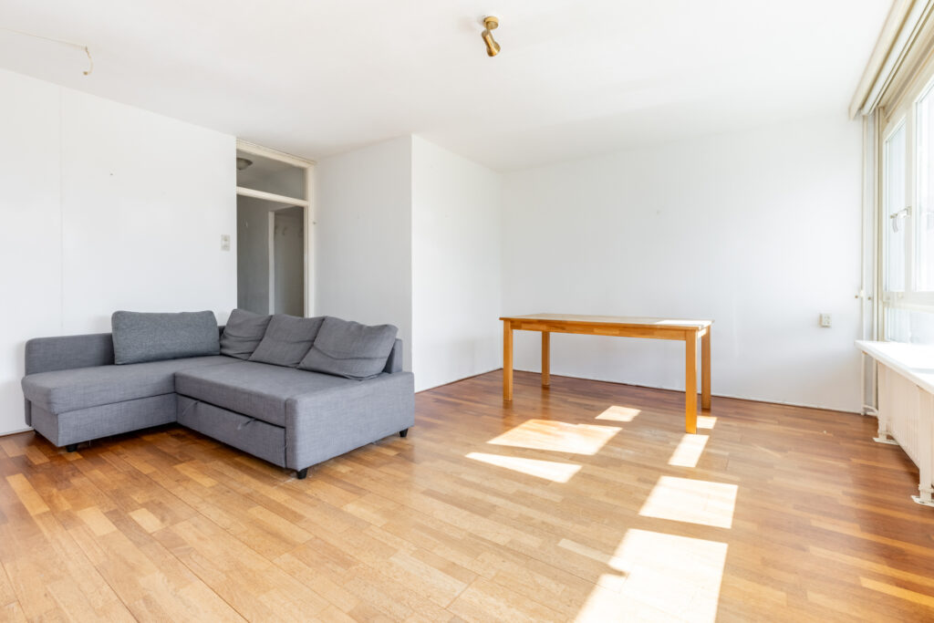 Minimalist living room with gray sofa and wooden table.
