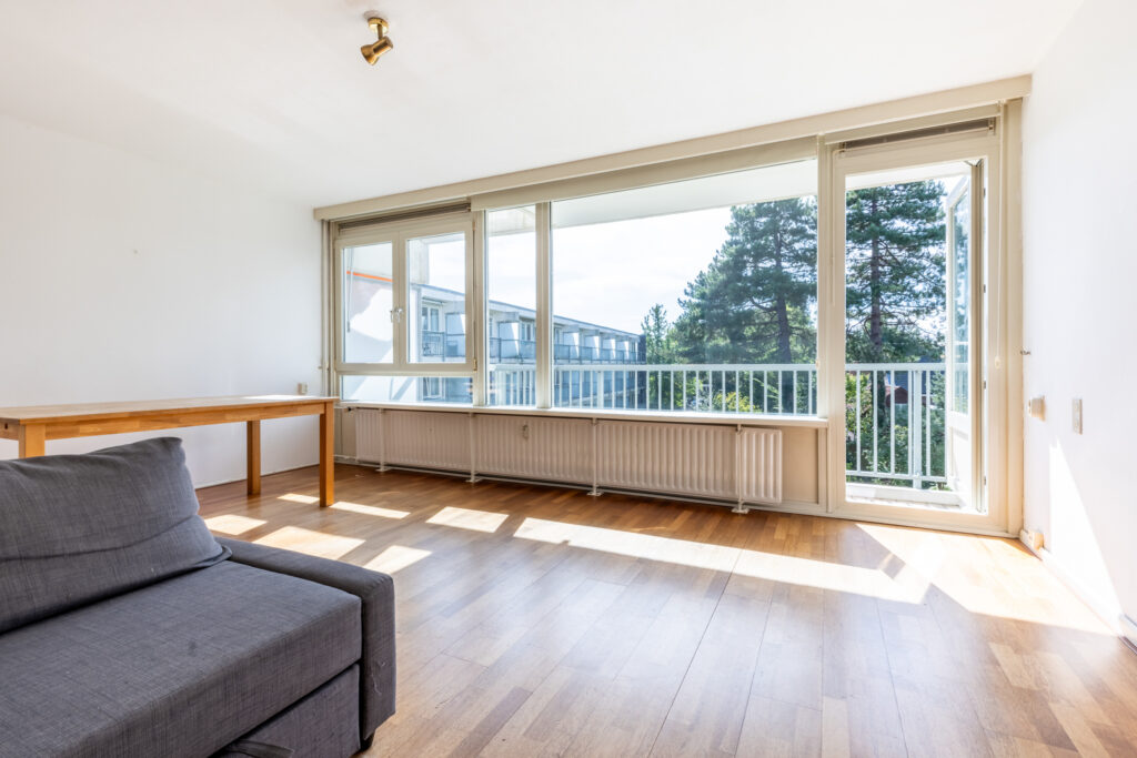 Bright living room with large windows and balcony view.