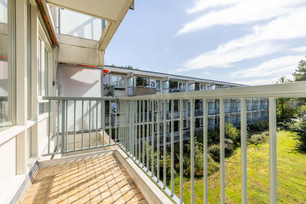 Sunny apartment balcony overlooking a green courtyard.