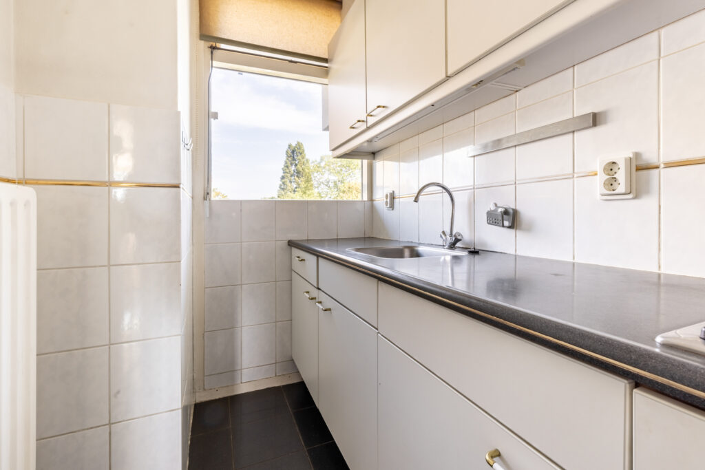 Compact kitchen with white cabinets and tiled walls.