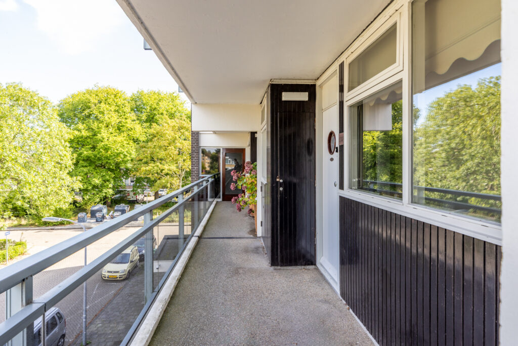 Apartment balcony with trees and street view.