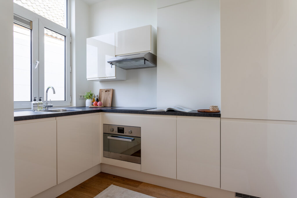 Modern white kitchen with natural light and appliances.