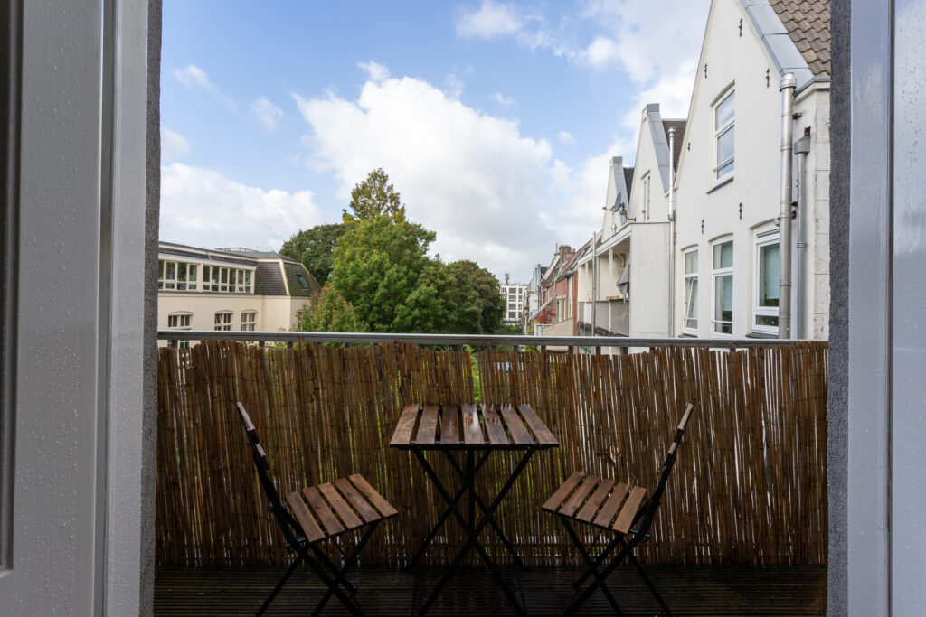 Cozy balcony with wooden chairs and table.