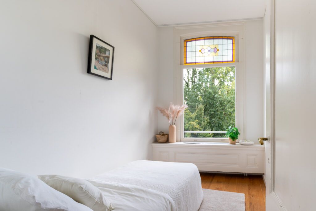 Cozy bedroom with stained glass window view.