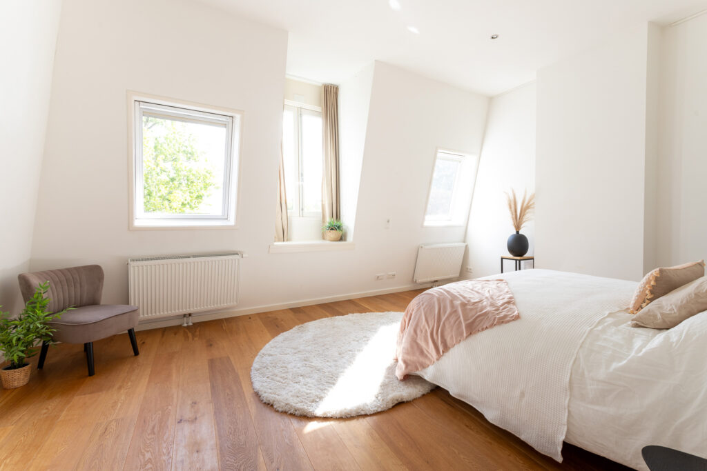 Bright bedroom with wooden floor and cozy decor.