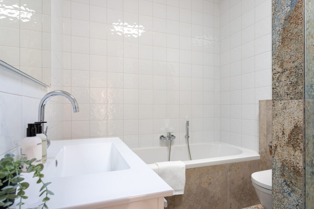 Modern bathroom with sink, bathtub, and decorative tiles.