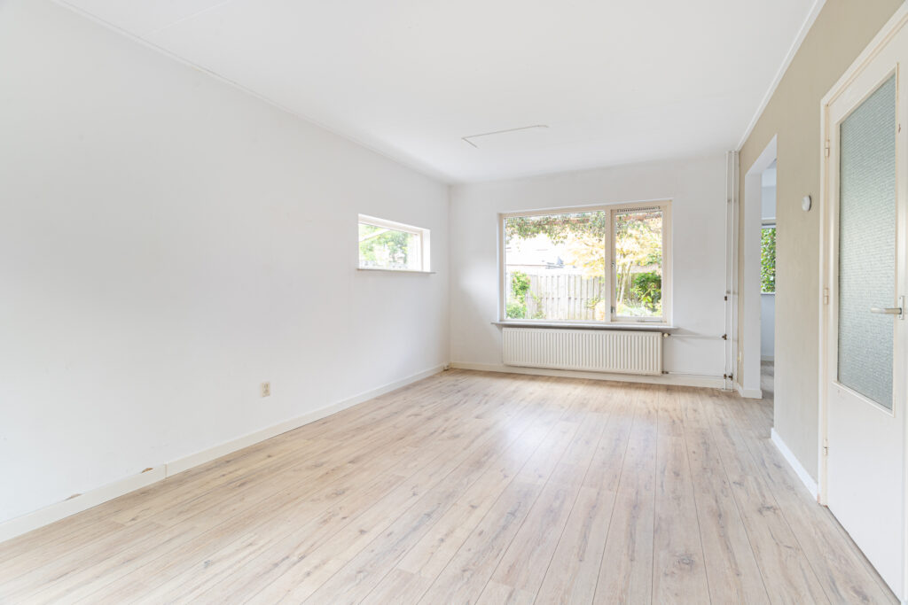 Empty bright room with wooden floor and large windows.