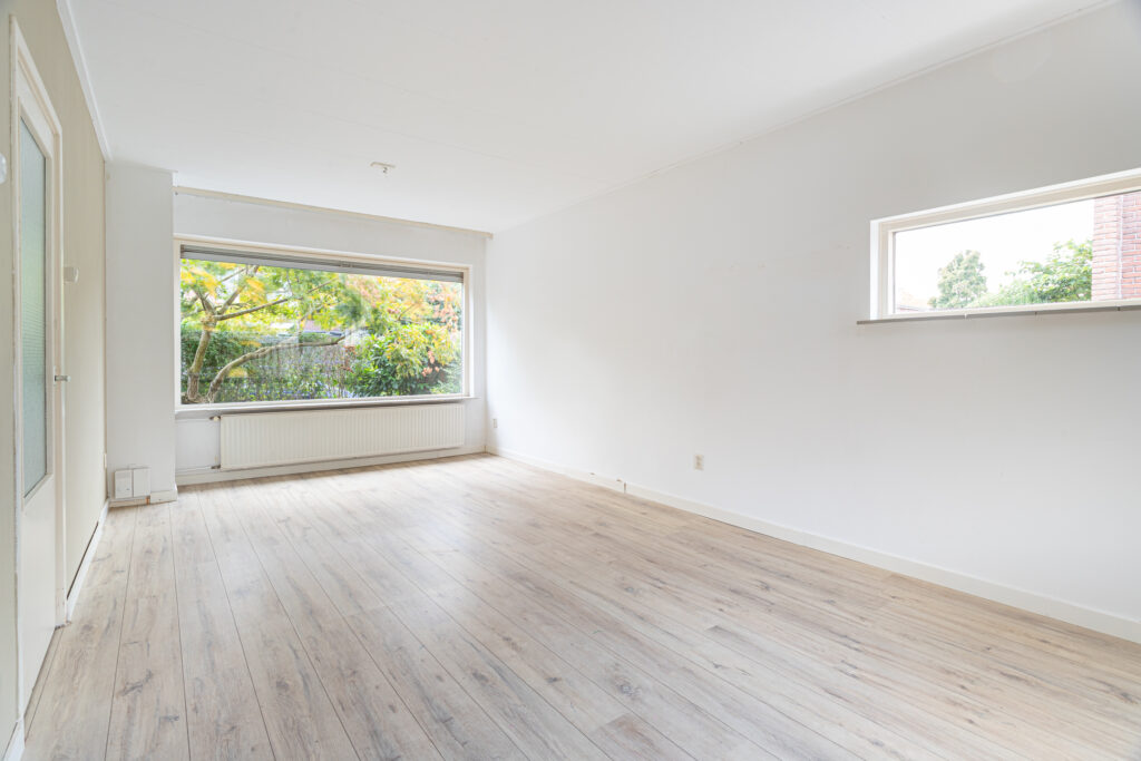 Bright empty room with wooden floor and large window.