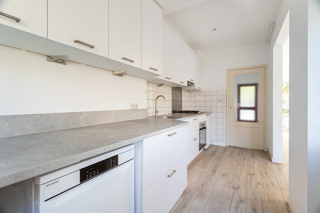 Modern kitchen with white cabinets and wood floor.