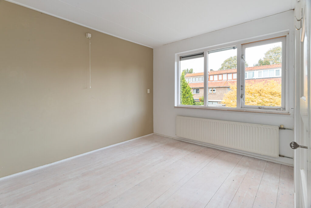 Empty room with beige walls, large windows.
