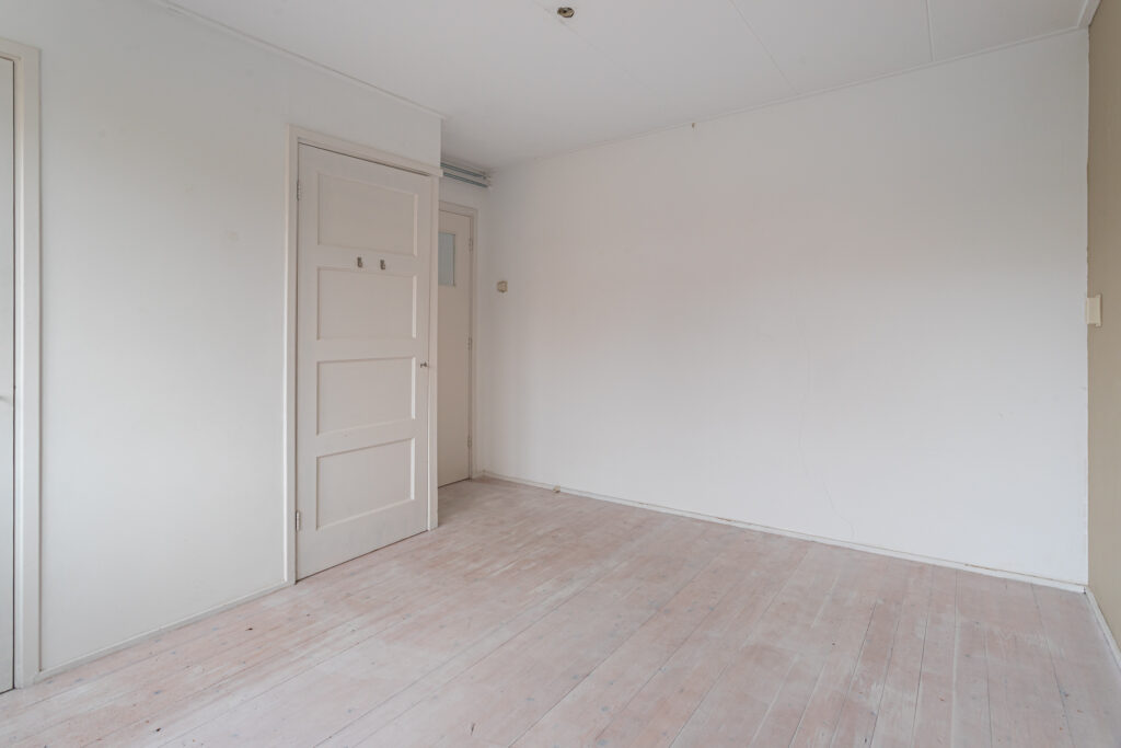 Empty room with white walls and wooden floor.