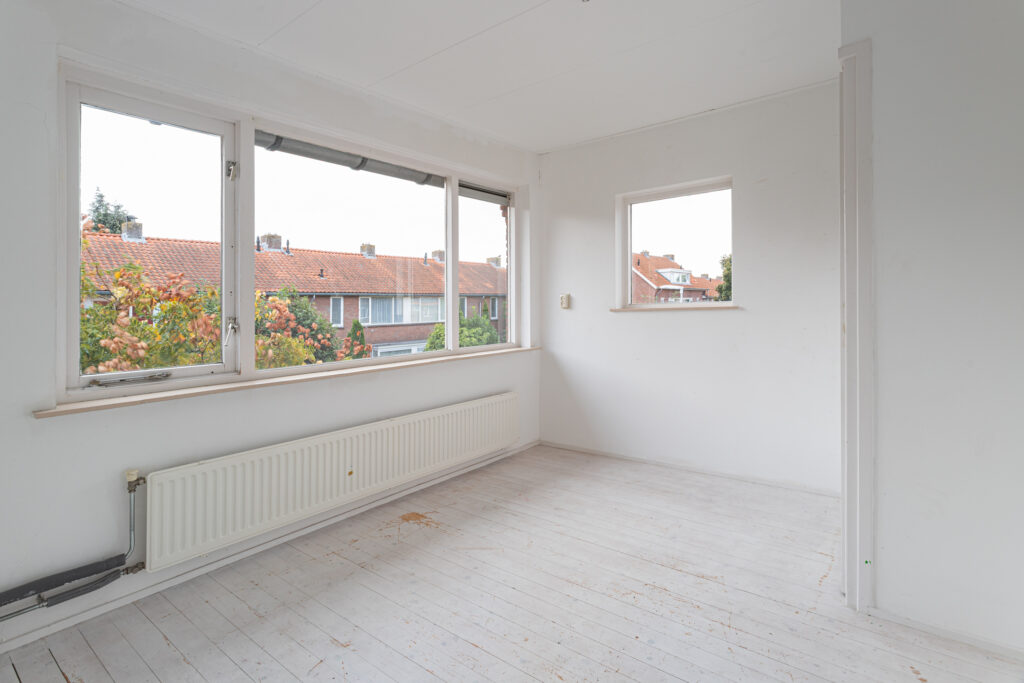 Empty room with large windows and radiator