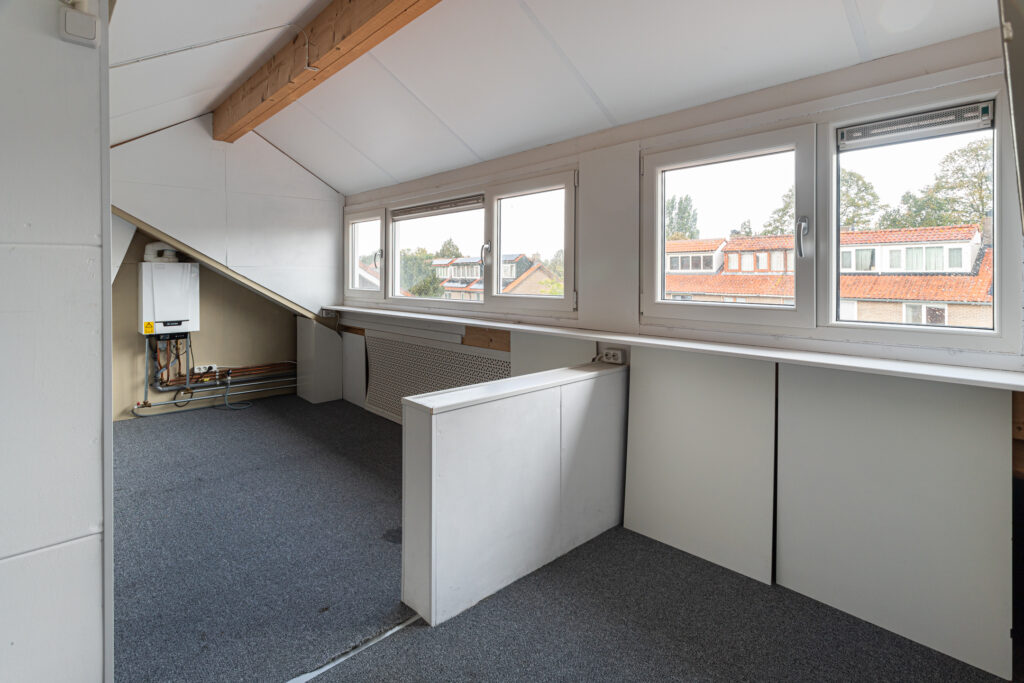 Bright attic room with windows and heating system.