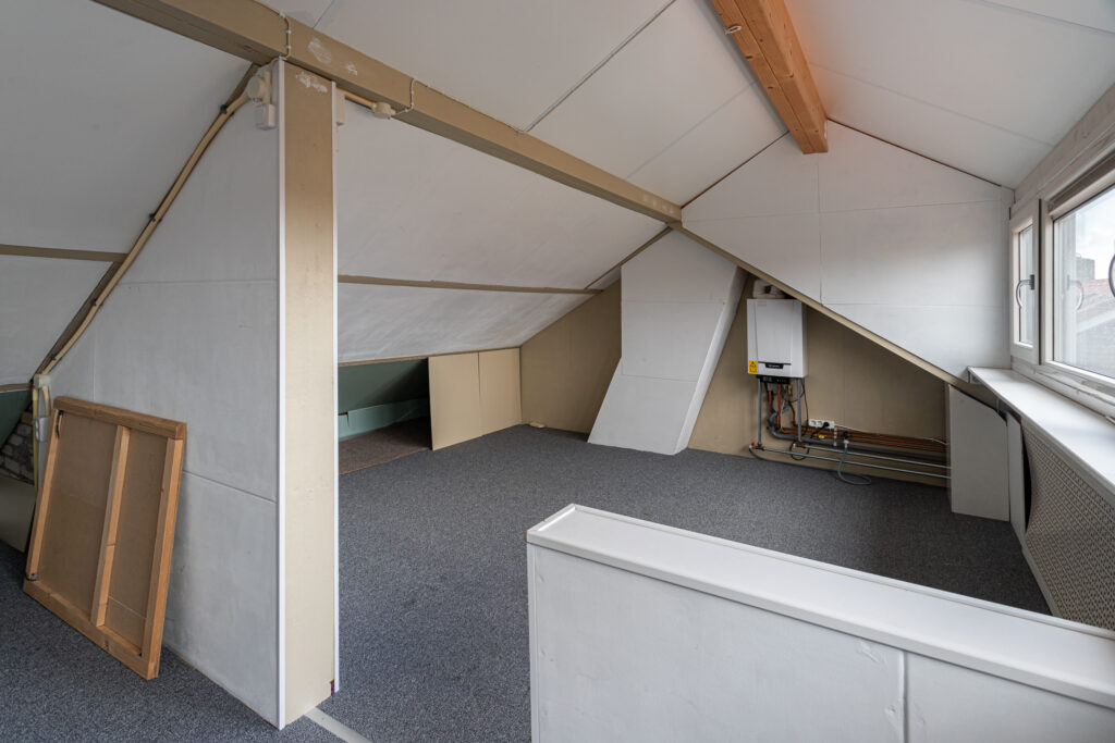 Empty attic space with sloped ceiling and carpeted floor.