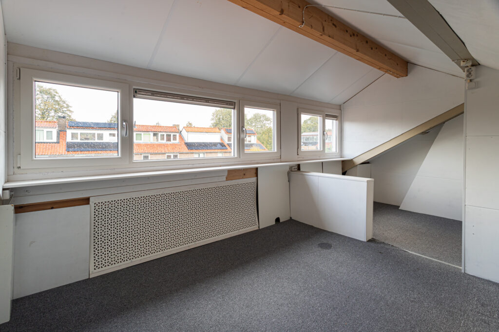 Bright attic room with windows and carpet