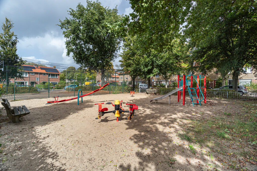 Empty playground with seesaw and slide on sand.