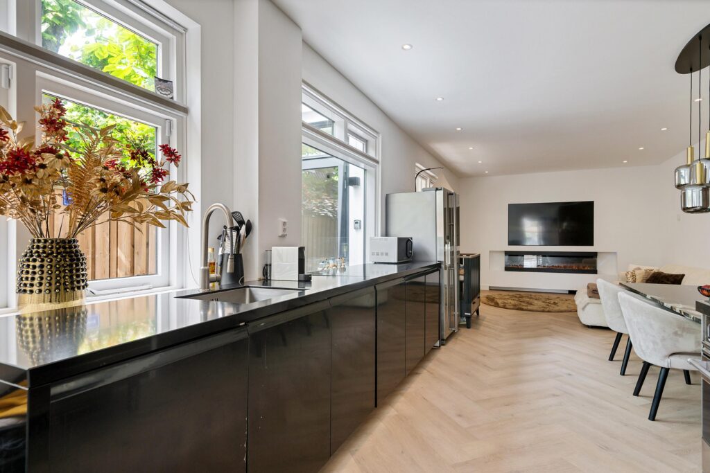 Modern kitchen and living room with large windows.