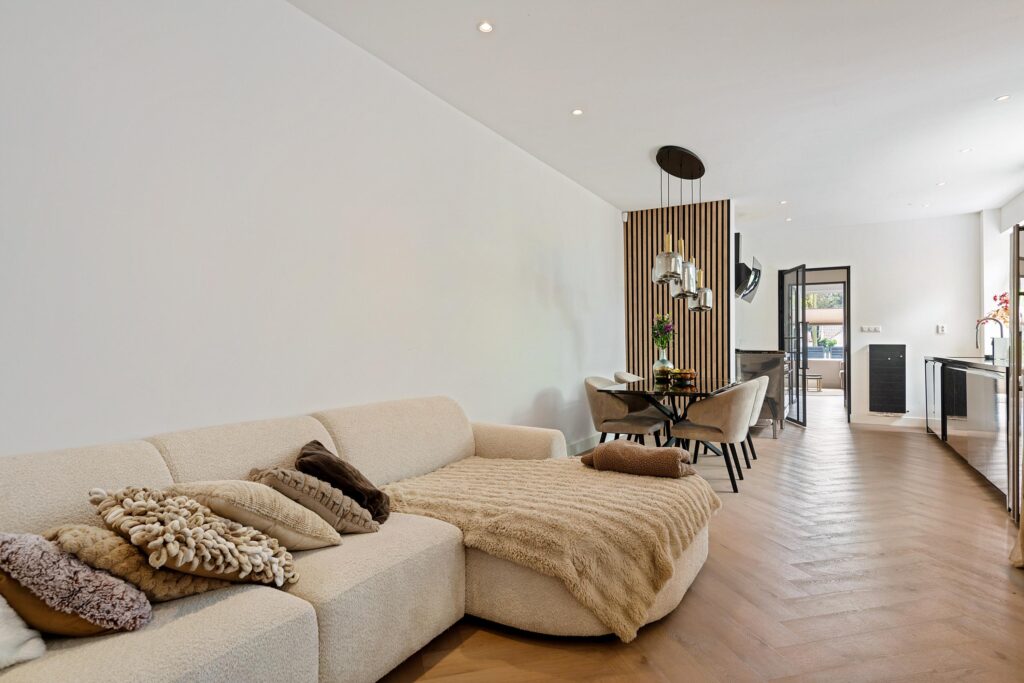 Modern living room with beige sofa and dining area.