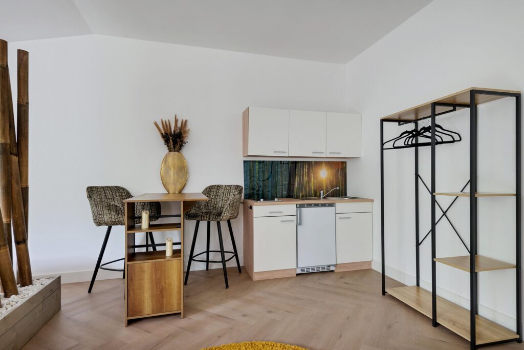 Modern kitchenette with bar stools and storage unit.