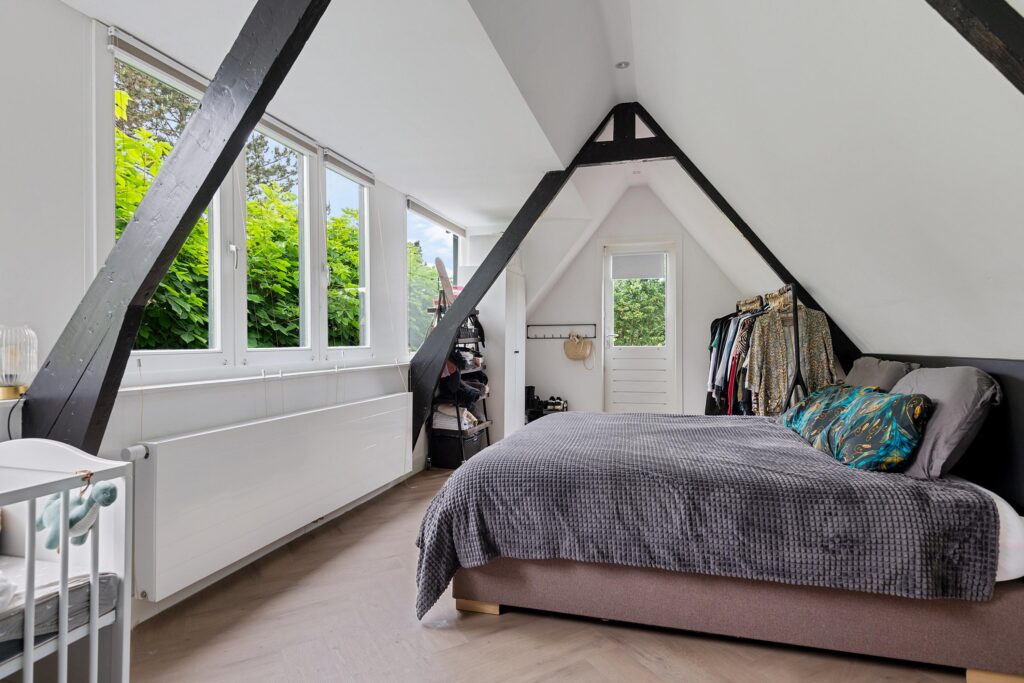 Cozy attic bedroom with large windows and wardrobe.