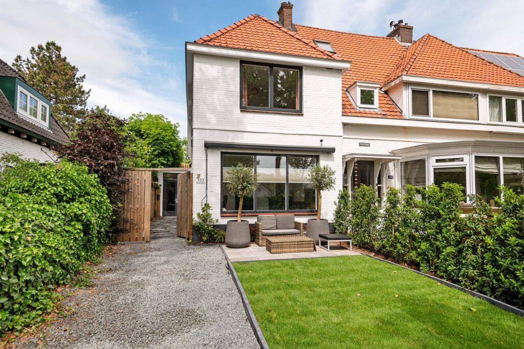 Charming house with lush garden and red roof.