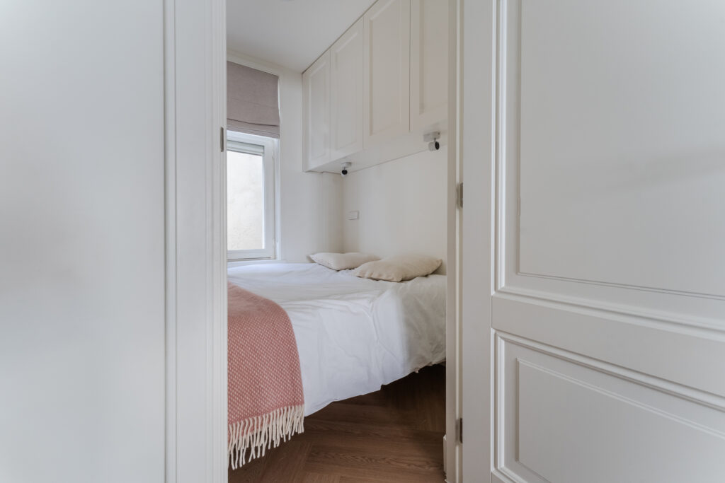 Cozy small bedroom with window and pink blanket.