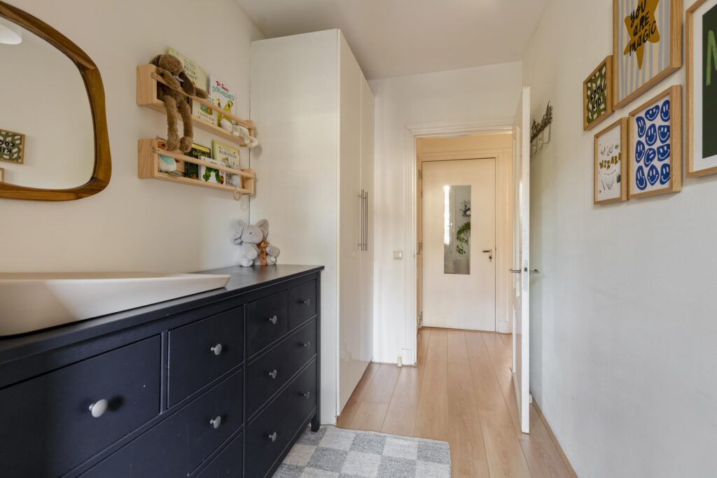 Nursery room with dresser, shelves, and wall art.