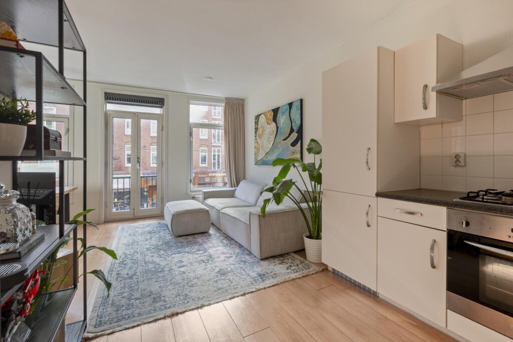 Modern living room with kitchen and large windows.