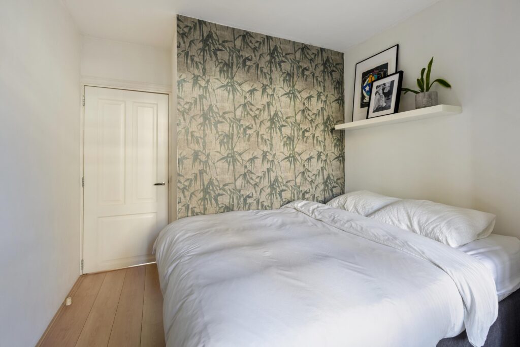 Cozy bedroom with bamboo wallpaper and white bed.