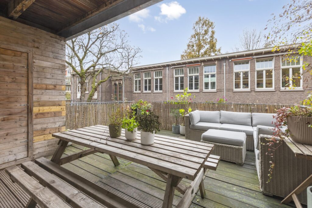Cozy patio with wooden furniture and potted plants.