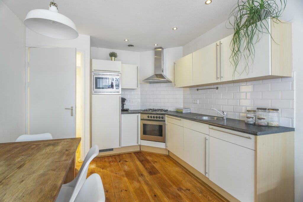 Modern kitchen with wooden floor and white cabinets.
