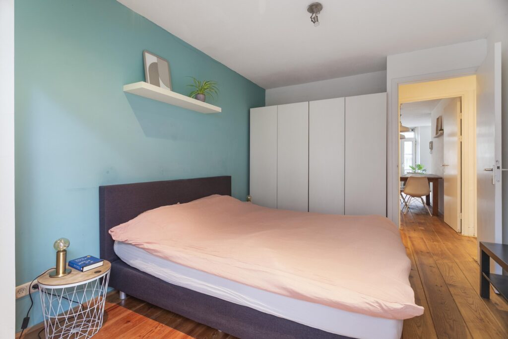 Cozy bedroom with teal wall and modern furnishings.