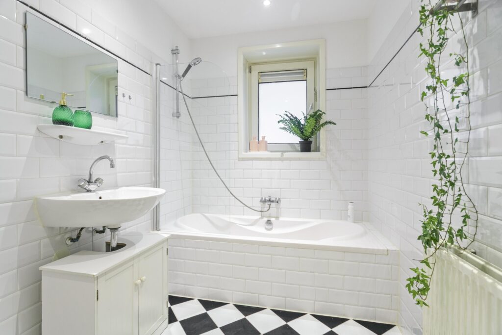 Modern white bathroom with tub and plants.