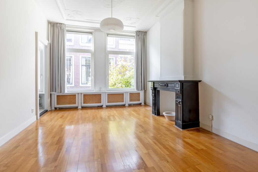 Spacious, empty room with wooden floors and fireplace.