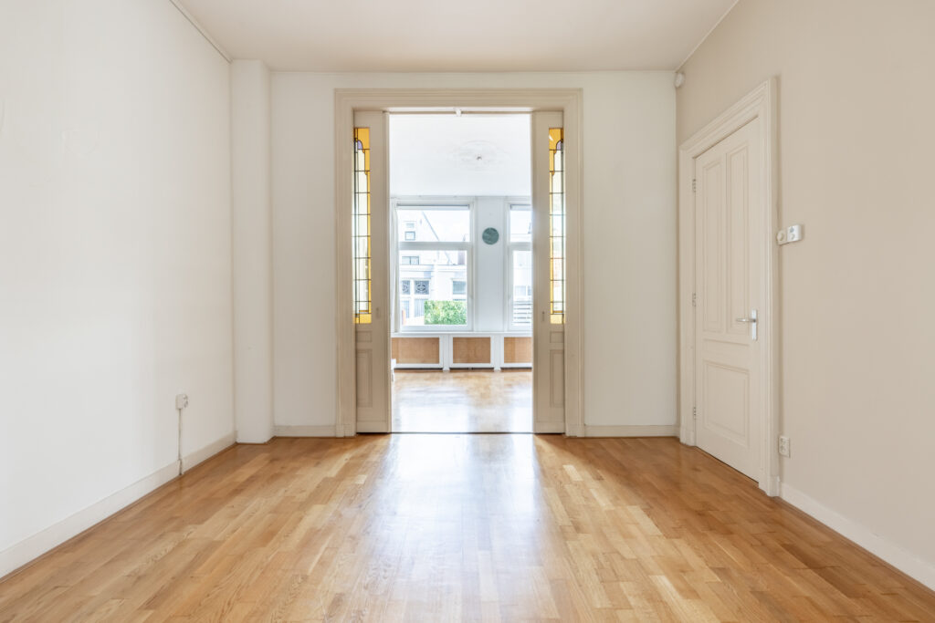 Spacious room with wooden floor and glass doors.