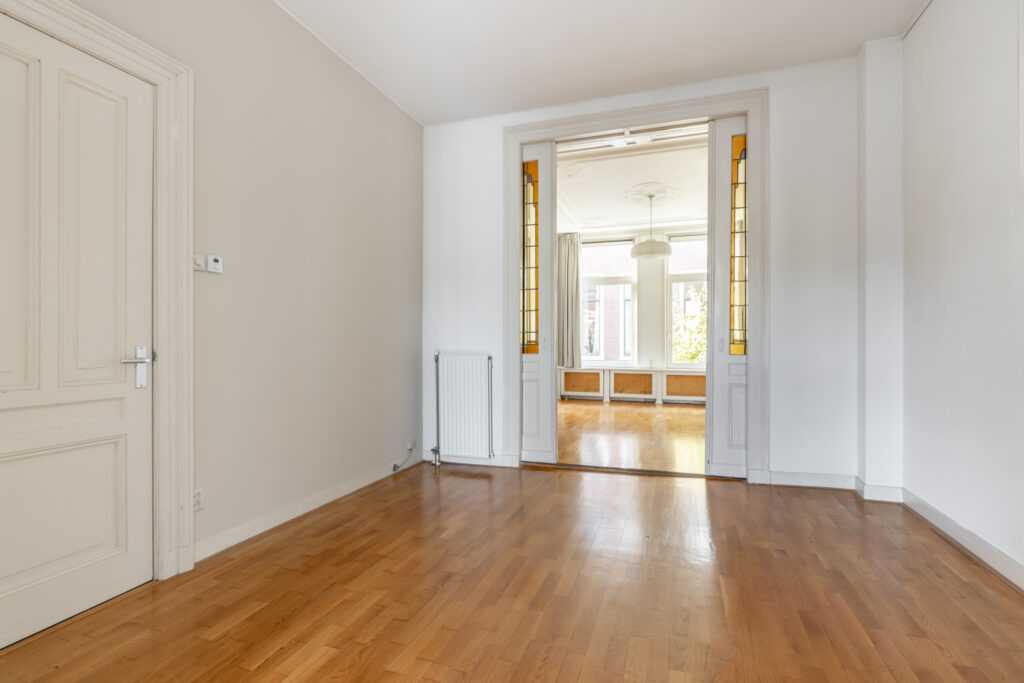 Spacious room with wooden floors and large windows.