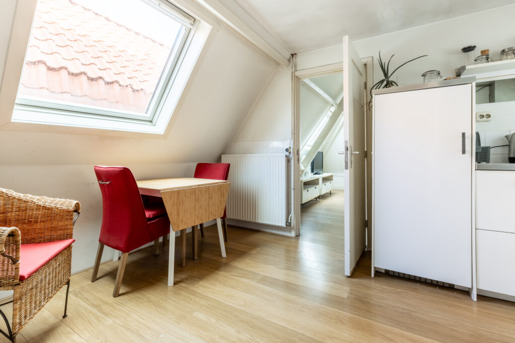 Cozy attic room with red chairs and skylight.